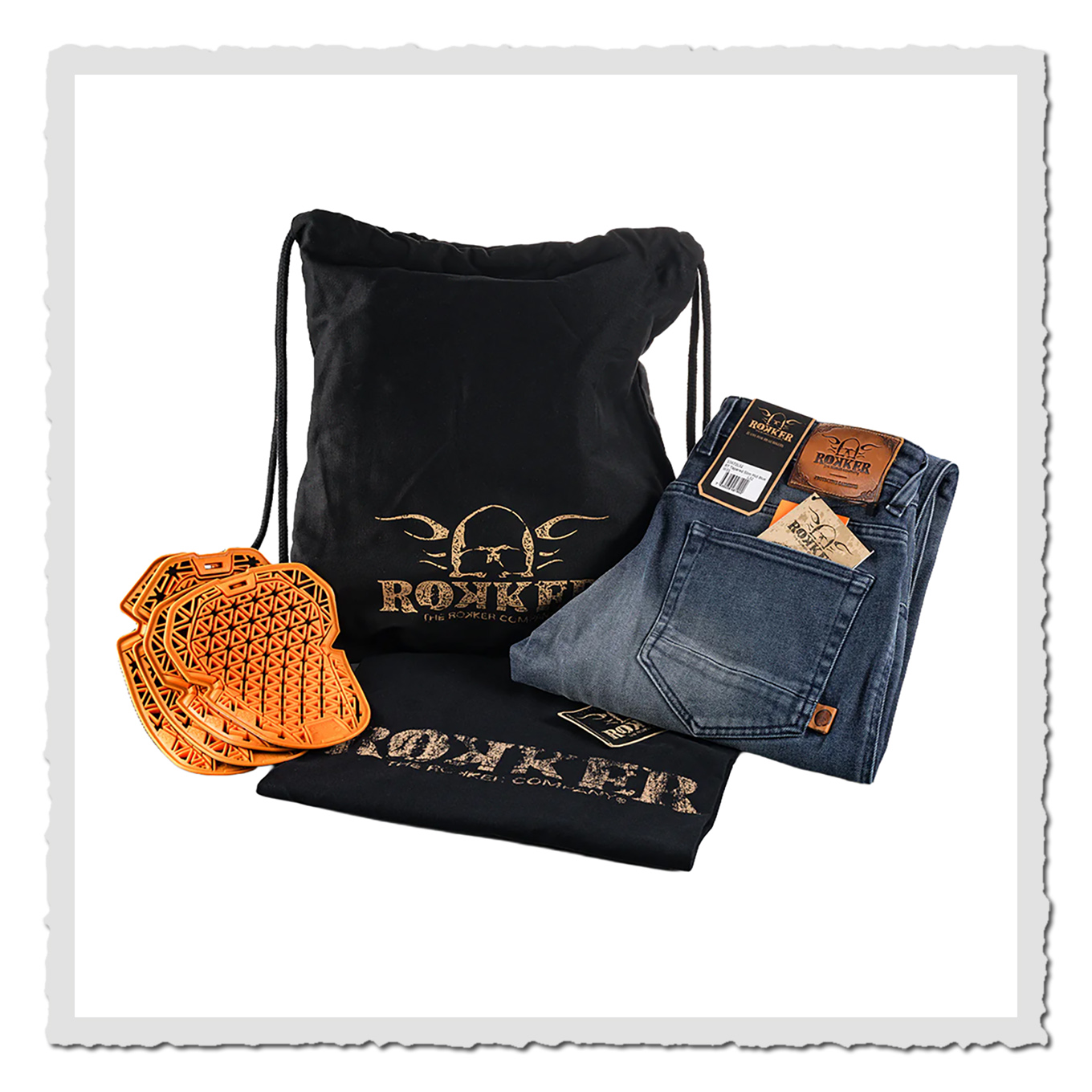 Gefaltete Jeans, schwarzer Beutel, schwarzes Shirt und orange Einsätze auf weißem Hintergrund.